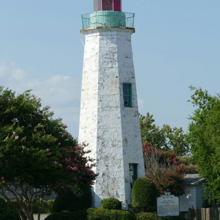 Historic lighthouse with surrounding greenery.