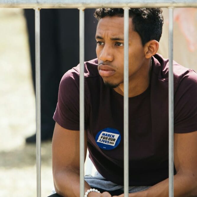 A person sitting with a badge of march for our lives on his tshirt