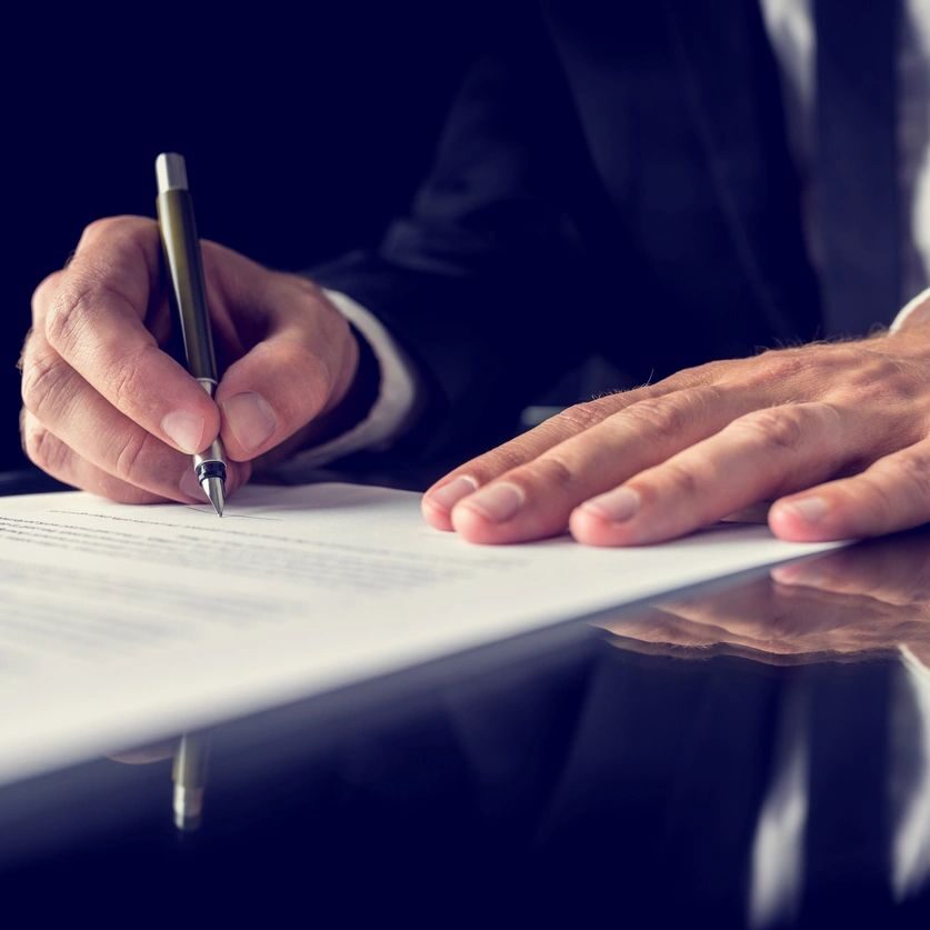 Person signing a document with a pen.